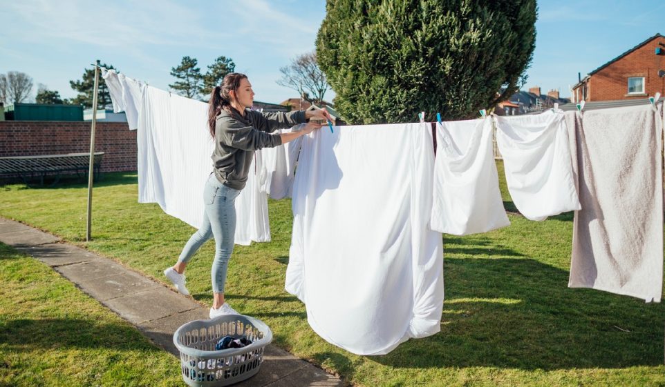 Female nursing student doing her washing hanging it up and collecting it in her garden.